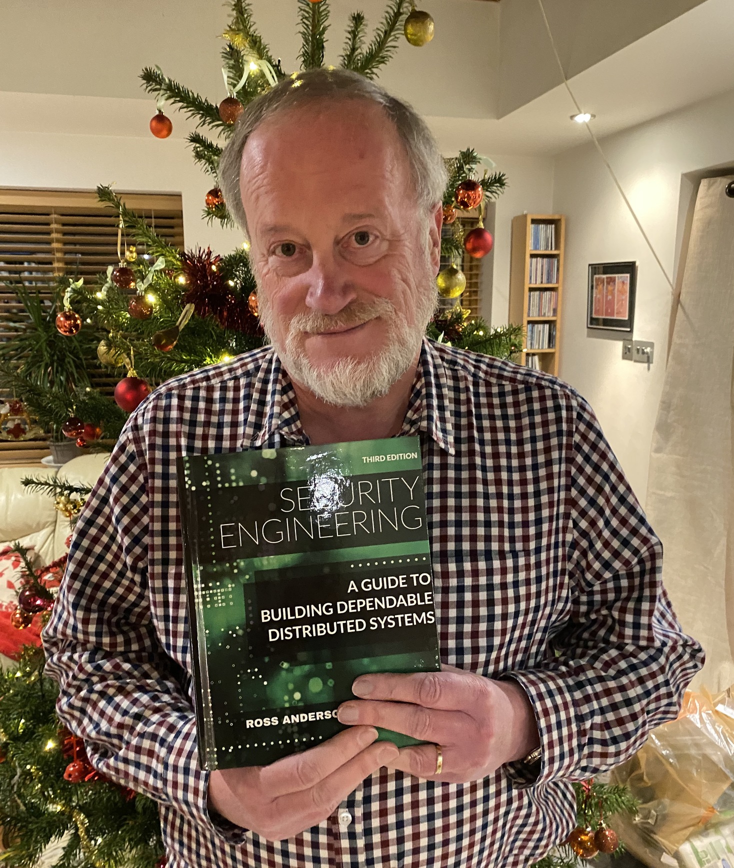 Portrait photo of Ross Anderson holding a textbook