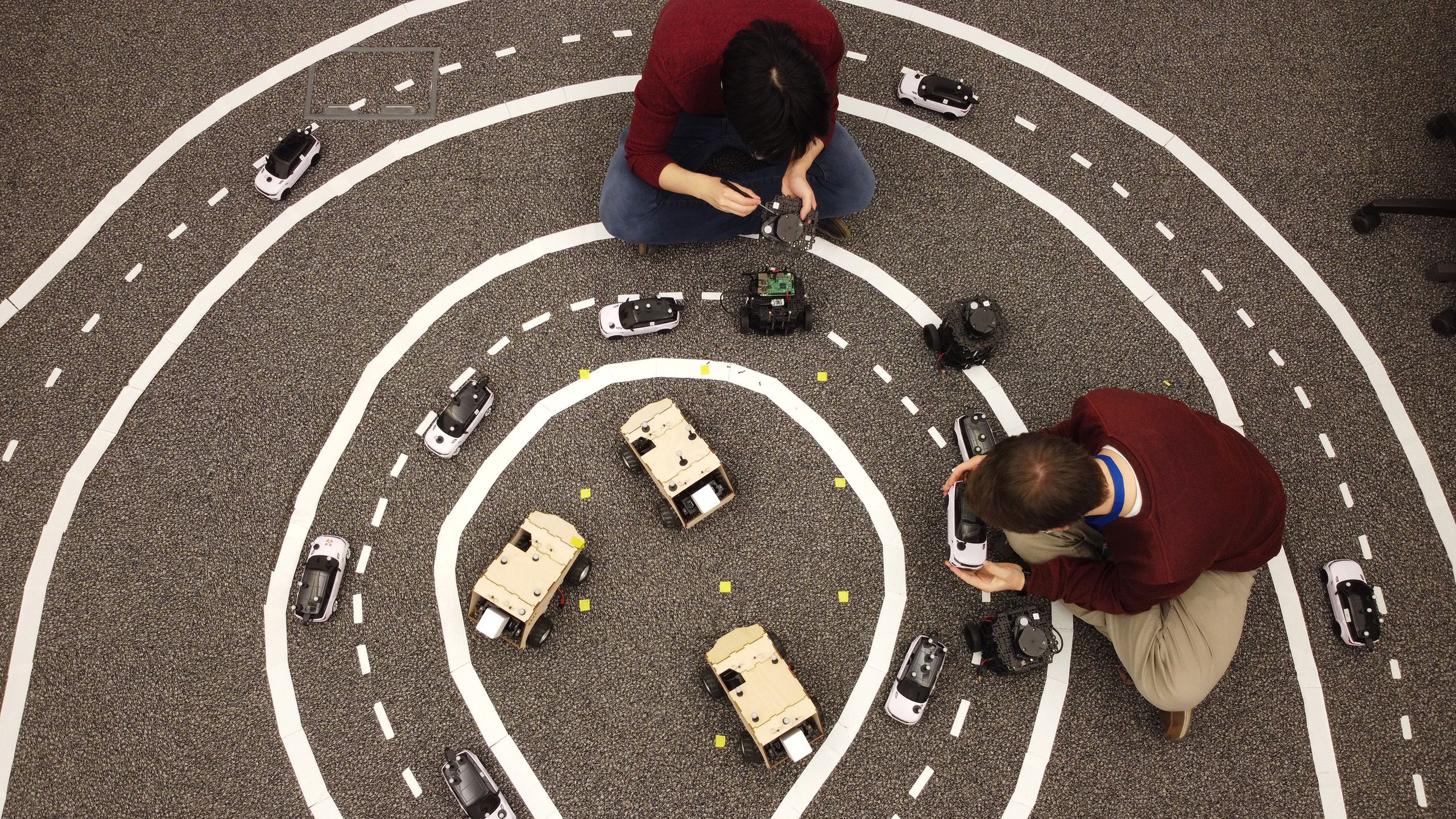 Image of researchers in the Prorok Lab, working on miniature robotic cars as they model the driverless cars of the future.